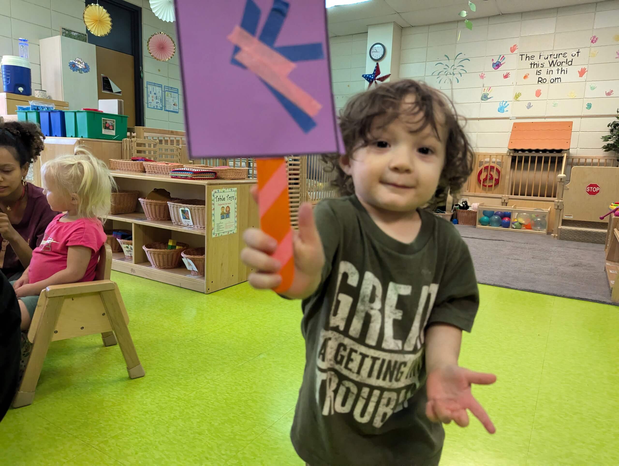 Child at 2nd St. location showing off an art project. 